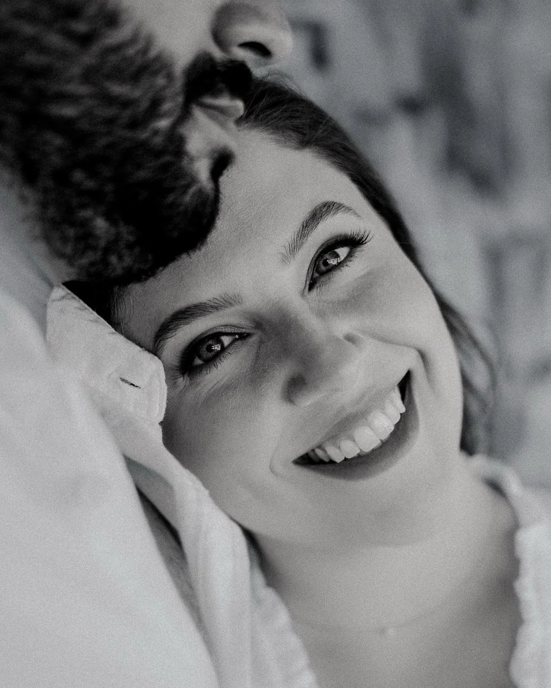 Retrato em preto e branco de uma mulher sorrindo, deitada